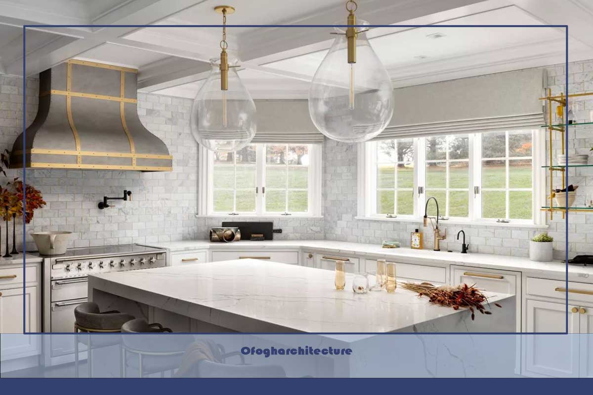 آشپزخانه با جزیره مرمر، آویزهای بزرگ شیشه‌ای شفاف، پشتی سنگ مرمر، قفسه بندی باز، جزئیات برنجی، پرده